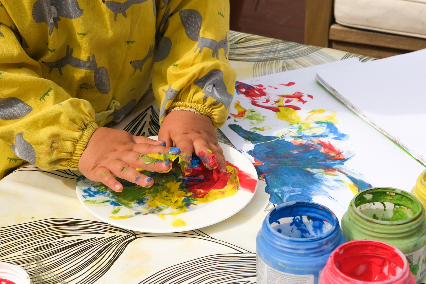 Early childhood development activity: finger painting outside on a sunny day